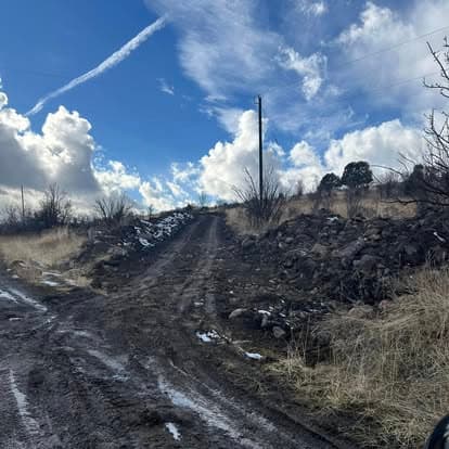 Rugged dirt road with rocky terrain under a blue sky and scattered clouds.