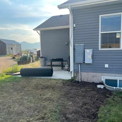 Side of a house with gray siding, electrical panel, and landscaping in progress.